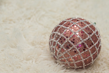 Pink christmas ball with sequins on a beige fleecy blanket. Selective focus