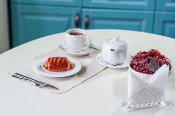 Cake with strawberries and black tea on the table in a cozy coffee shop