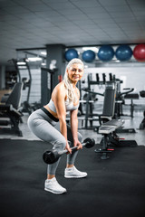 Obraz na płótnie Canvas Blonde doing bent over barbell row exercise in gym.