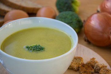 Close-up of healthy lunch, vegetable soup from broccoli, and bread, onion, eggs in the back, food on a wooden table, healthy eating