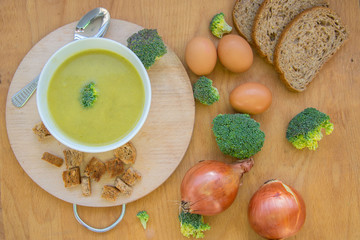 Close-up of healthy lunch, vegetable soup from broccoli, and bread, onion, eggs in the back, food on a wooden table, healthy eating