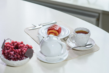 Cake with strawberries and black tea on the table in a cozy coffee shop