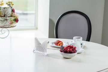 Cake with strawberries and black tea on the table in a cozy coffee shop