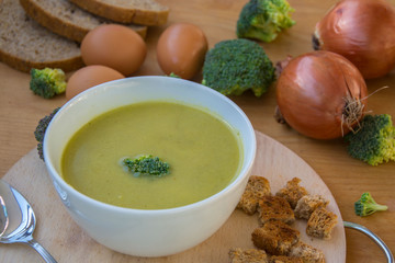 Close-up of healthy lunch, vegetable soup from broccoli, and bread, onion, eggs in the back, food on a wooden table, healthy eating