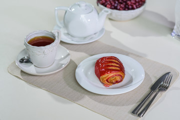 Cake with strawberries and black tea on the table in a cozy coffee shop