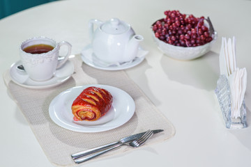 Cake with strawberries and black tea on the table in a cozy coffee shop