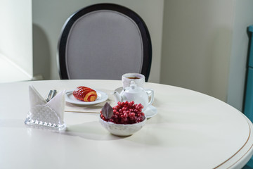 Cake with strawberries and black tea on the table in a cozy coffee shop