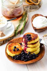 Cottage cheese pancakes and blueberries on a white wooden table, selective focus