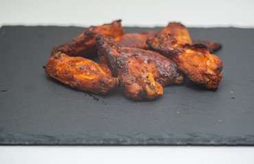 spicy chicken wings in the foreground on cast iron cooking.