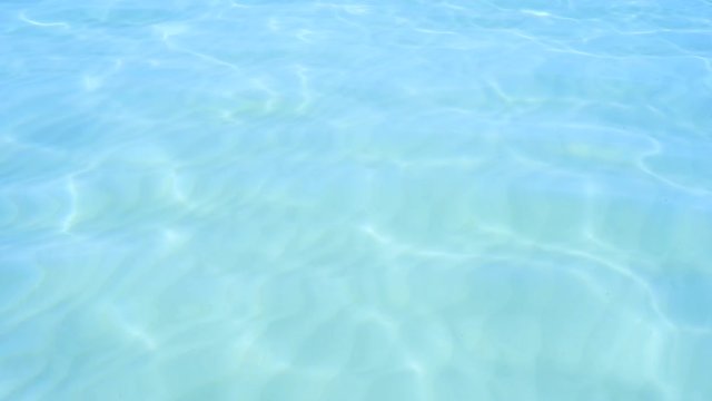 Blue clear ocean water. White sand at the bottom. Solar reflections