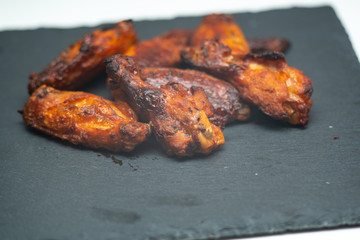 spicy chicken wings in the foreground on cast iron cooking.