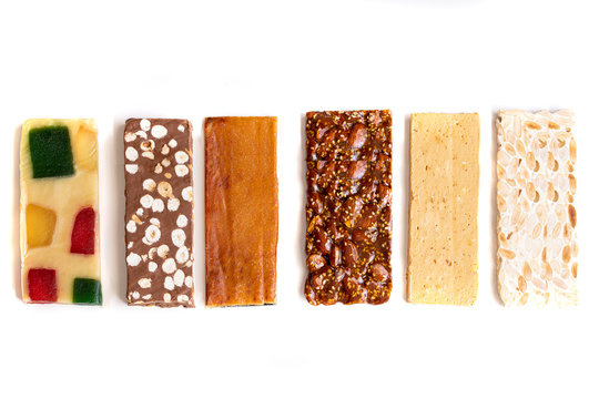 Different Spanish turron or nougat, hard almond, soft almond, chocolate, burnt egg yolk guirlache, glace fruit nougat. Spanish Christmas sweet background.