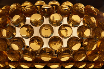 Close-up of source of light with semitransparent balls or bubbles. Industrial structure featuring regular pattern of glowing round elements. Abstract geometric background in yellow or golden color. 