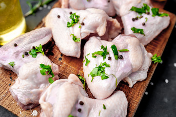 raw chicken wings on a cutting board with spices on a stone background 