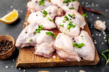 raw chicken wings on a cutting board with spices on a stone background 