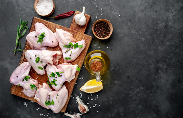 raw chicken wings on a cutting board with spices on a stone background with copy space for your text