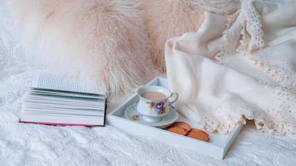 Cozy coffee time with fluffy pillows, books and sweets