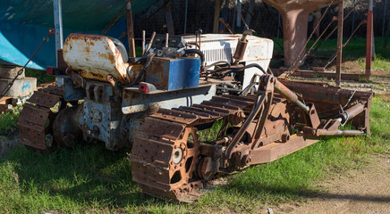 Fototapeta na wymiar A small old abandoned bulldozer is rusting in a yacht yard
