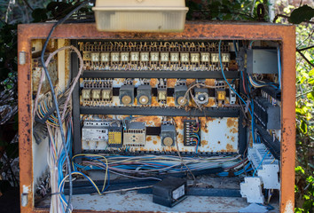 Rusty electric box with fuses and wires in the dump outside