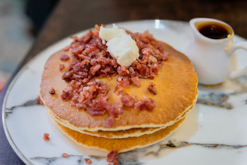 Pancakes topped crispy bacon and butter.