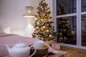 Cozy and comfortable evening bedroom with a beautiful Christmas tree and New year lighting and decorations.