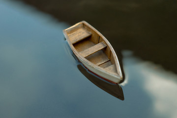 Small wooden boat on the water. A small boat is floating on the water with a reflection of the sky