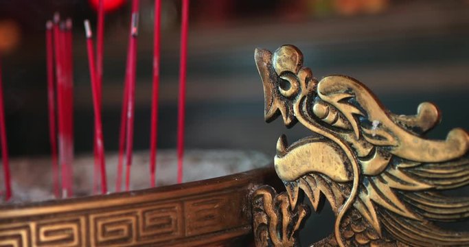 Burning incense sticks with smoke at Chinese traditional temple. Buddhism temple ceremony during Chinese New Year. Close-up view of praying incense offered in the Holy Temple in slow motion.