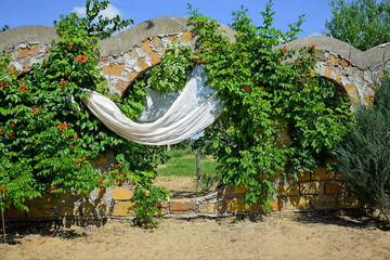 stone arch made of shell with a white curtain covered with vine