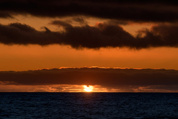 Natural marine landscape with amazing sunset over the ocean in Tenerife Canary Island Spain. Summer exotic vacation postcard from tropical island. Wonderful orange sunrise over the water behind clouds