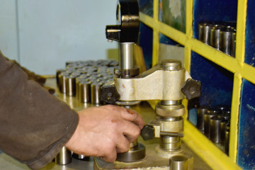The worker measures the rollers in height.