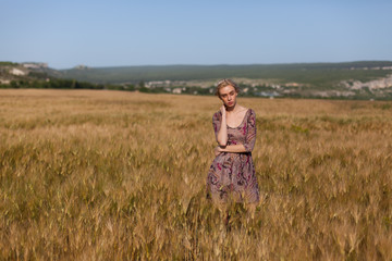 Beautiful fashionable blonde woman in a field of yellow ripe wheat