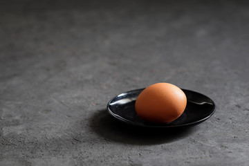 Still life egg on a black plate on a dark background