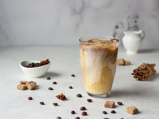 Cold brew coffee with spices and milk on light grey background. Spicy coffee with ice cubes.