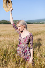 Beautiful fashionable blonde woman in a field of yellow ripe wheat