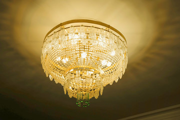 Vintage chandelier on the ceiling of the room in pastel colors.