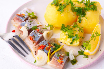 pieces of salted herring in spices with boiled potatoes