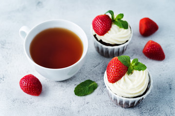 Chocolate cupcakes with cream cheese frosting, mint leaves and strawberries