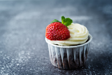 Chocolate cupcakes with cream cheese frosting, mint leaves and strawberries