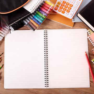 Busy student's desk with blank open notebook
