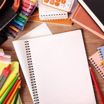 Busy student's desk with blank folded notebook