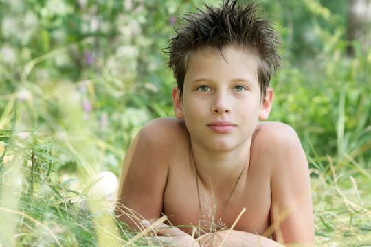 A Tanned Boy Of 12 Years Old Is Lying In The Grass. Russian	