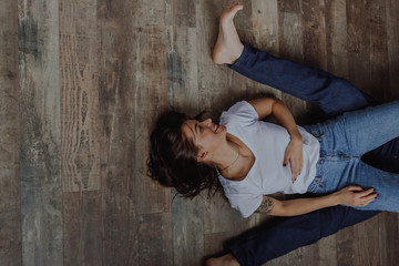 Smiling young woman laying on the wooden floor