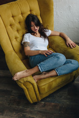 Beautiful young woman sitting in yellow armchair