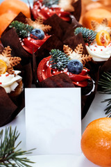 Christmas cupcakes for New Year's decoration. Set of pastries decorated with berries, stars and spruce branches. Place for text.