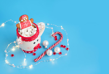 Christmas Cup of hot chocolate with marshmallow and gingerbread man on a blue background. Creative concept of New year and Christmas