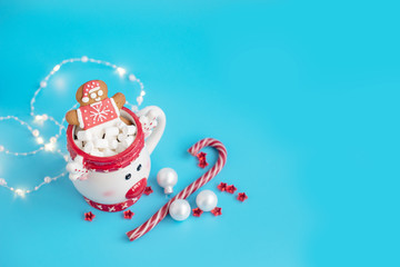 Christmas Cup of hot chocolate with marshmallow and gingerbread man on a blue background. Creative concept of New year and Christmas
