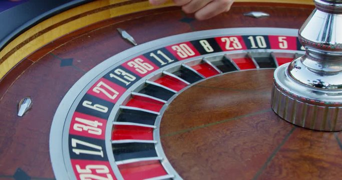Close up shot of a roulette wheel, as the ball is slowly spinning down the numbers. Landing on a black eight.