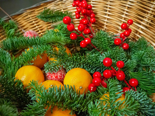 Christmas composition of  tangerines, fir branches,  red berries and balls in a basket. Christmas and New Year background