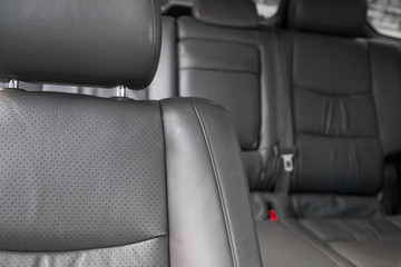 Fototapeta premium Upholstery of the seats of the passenger compartment of a luxury car with gray perforated genuine leather in a workshop for hauling vehicles with a seam of thread.