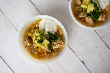 Flavorful White Chicken Chili made with hearty beans, tender chicken, and a rich and creamy broth in slow cooker, garnished with sour cream and avacado